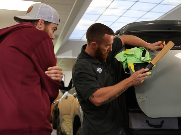 Two men working on a car in a showroom.