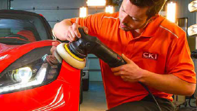 A man is polishing a red sports car.