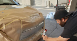 A man is painting a car with a brown paper.