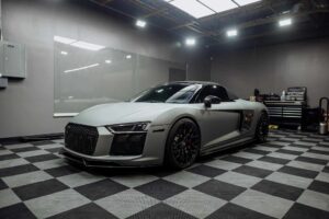 A silver audi r8 parked on a checkered floor.