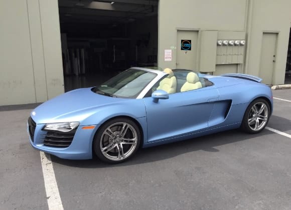 A blue audi r8 spyder parked in front of a garage.