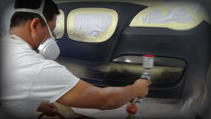 A man spraying paint on a car.