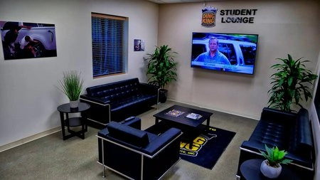 A student lounge furnished with black PDR training locations and equipped with a TV.
