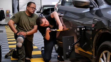 Two men working on a car in a garage at one of the PDR training locations.
