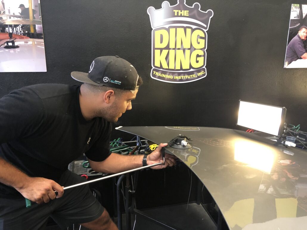 A man is working on a table with a ding king sign.