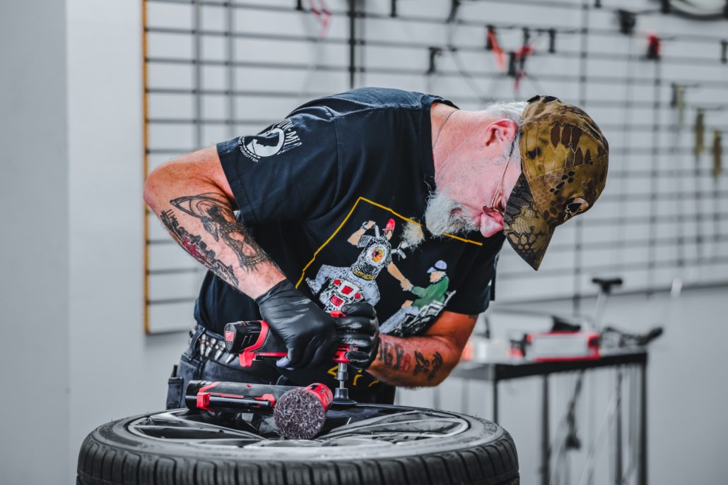A tattooed mechanic working on a tire.