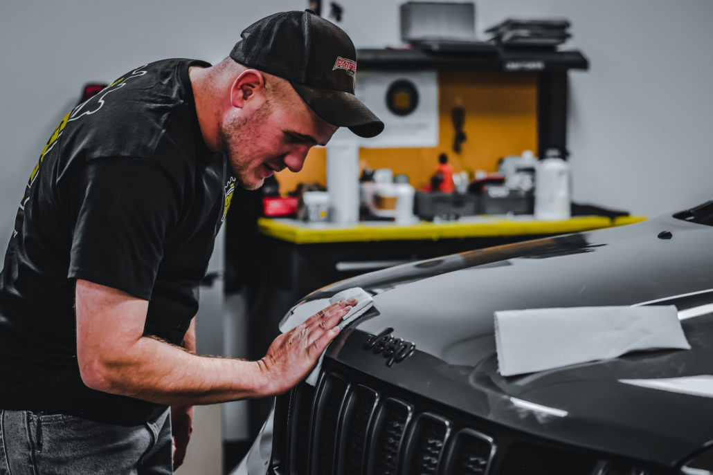 A man incorporating add-on profit centers by working on a black Jeep Cherokee.