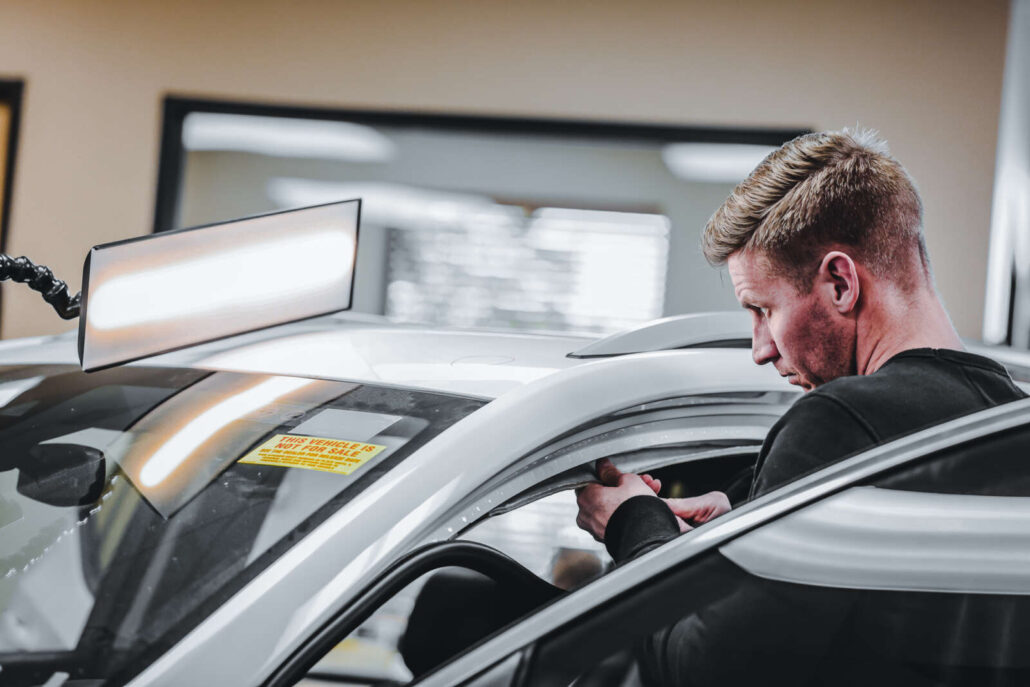 A man in Colorado focuses intently on detailing the interior of a car, honing his skills with specialized training.