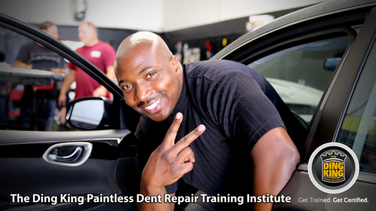 A smiling man leans out of a car window holding up a peace sign in a garage setting. Text on the image reads, "The Ding King Paintless Dent Repair Training Institute" and "Get Trained. Get Certified." Ideal for veterans seeking vocational rehabilitation opportunities.