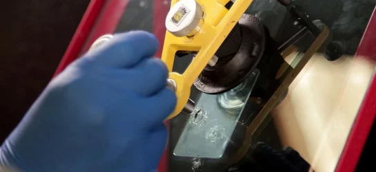 A person is using a tool to repair a windshield.