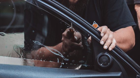 A man utilizing Add-On Profit Centers cleans a car window with a beard.